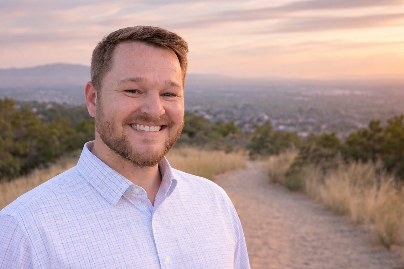 Austin Adams, local home buyer in Kaysville, Utah, smiling on a trail above the Wasatch Front at sunset